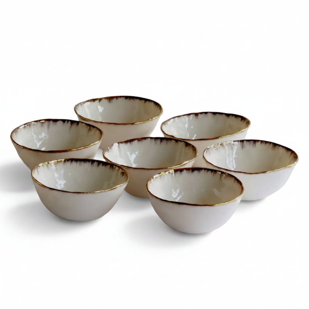 Set of white ceramic bowls with gold rims on a light gray background